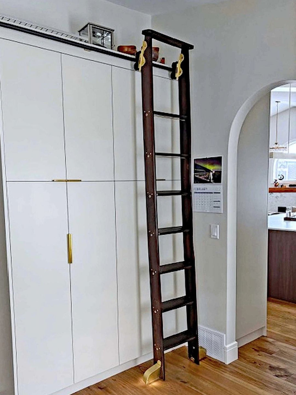Rolling ladder on tall white built in cabinets.
