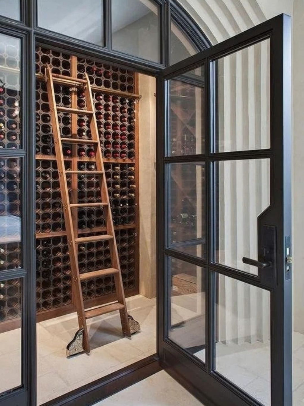 Rolling ladder inside a glass enclosed wine cellar.