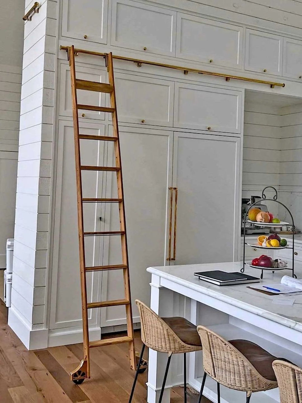 Rolling kitchen ladder on tall white cabinets.