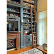 Library ladder kit on dark built in bookshelves beside a fireplace.