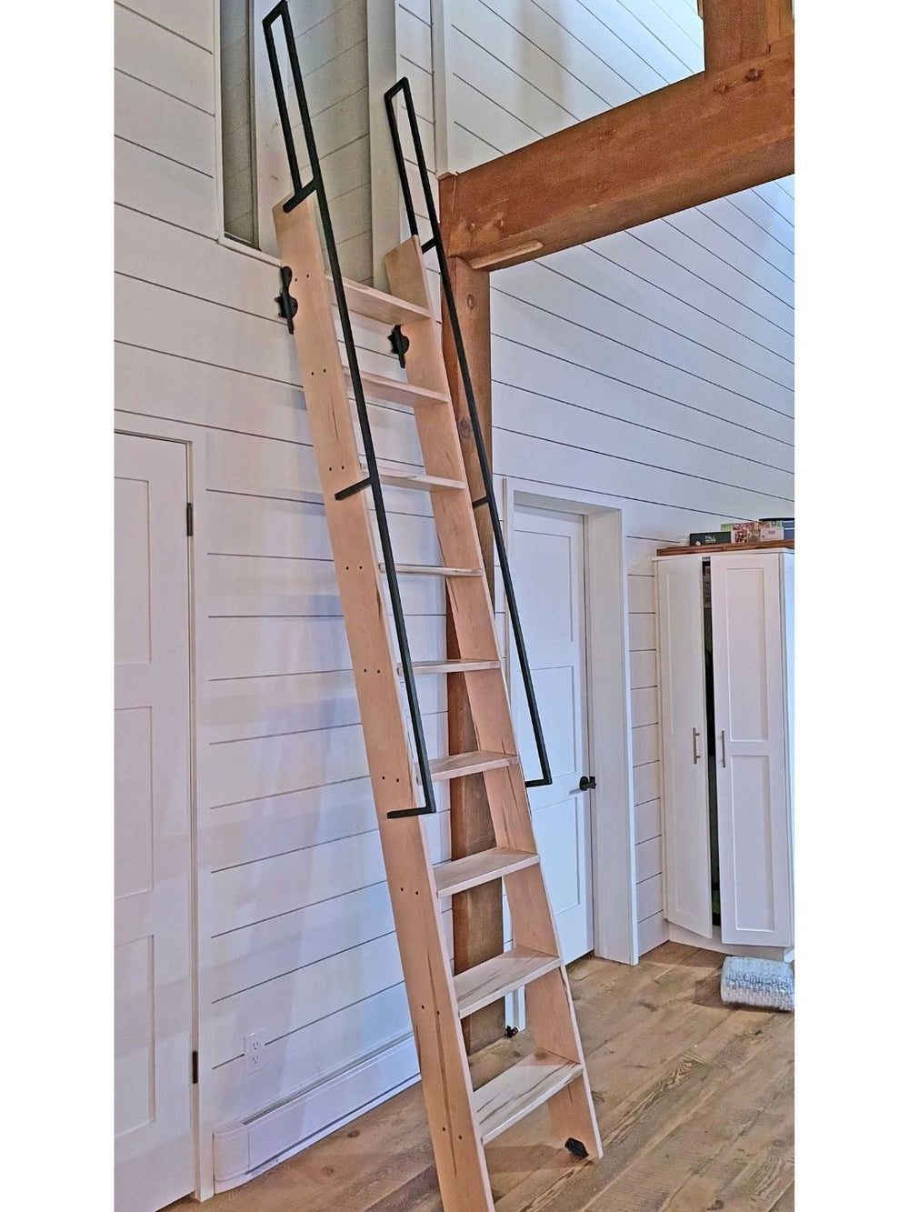 Muskoka loft ladder with steel handrails leading to a loft.